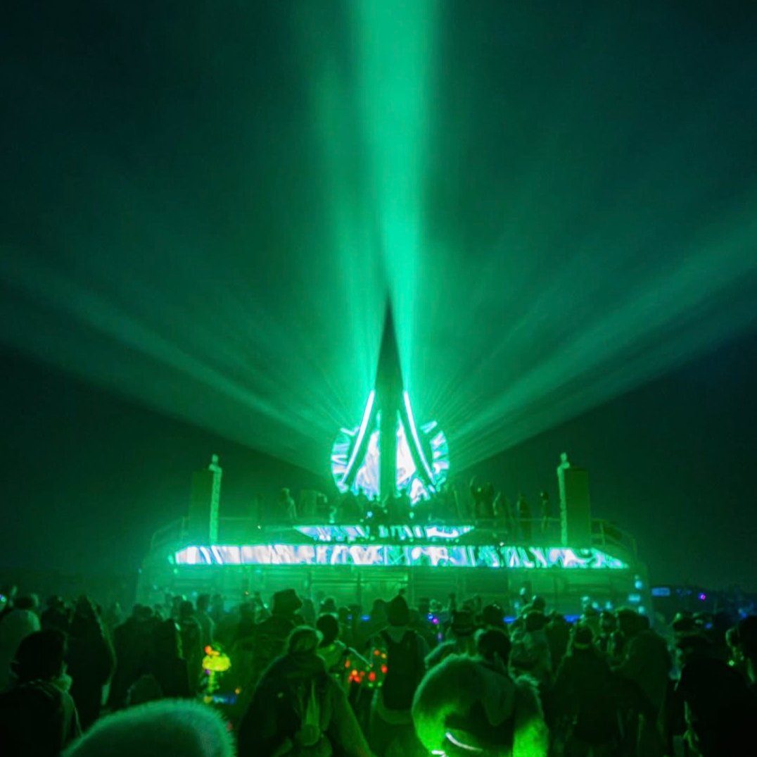 The Trion art car stage with green lasers over the crowd, Burning Man 2026